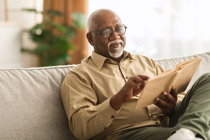 senior man reading a book on the couch